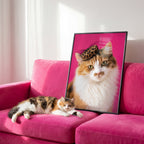 A calico cat lounges on a pink sofa beside a framed personalized pet art portrait of the same cat wearing a leopard print hat