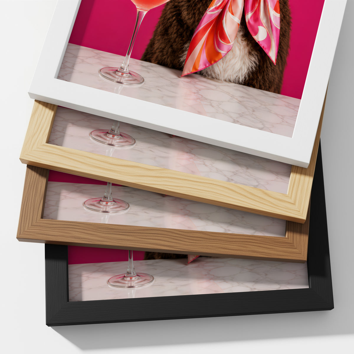 Four picture frames in white, natural wood, espresso, and black, stacked diagonally to show the different frame colors. Each frame contains a colorful art print featuring a pink background, a cocktail, and a dog wearing a patterned silk scarf.