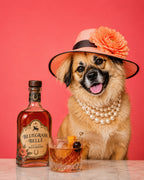 A small tan dog wearing a pink straw hat with a large orange flower, pearl necklaces, and a black band, sitting beside a bottle of Bluegrass Belle Bourbon whiskey and a rocks glass on a pink background.